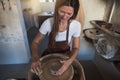 Artisan shaping clay on a pottery wheel in her workshop