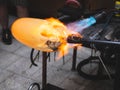 Artisan working with malleable glass and heating it with gas burner Royalty Free Stock Photo