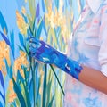 Artisans hand, adorned in blue, brings vibrant canvas to life