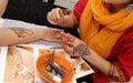 Artist applying henna tattoo on women hands Royalty Free Stock Photo