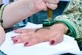 Artist applying henna tattoo on women hands. Mehndi is traditional Indian decorative art. Close-up, top view Royalty Free Stock Photo