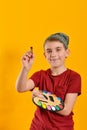 The artist boy holds a palette with paints in one hand, and a brush in the other Royalty Free Stock Photo