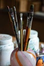 Artist brushes gathered in a pink and orange glass vase.