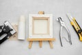 Artist canvas on wooden easel, canvas in roll, canvas stretcher pilers, knife and staple gun on marble background. Royalty Free Stock Photo