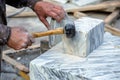 artist chiseling marble block with mallet