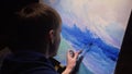 Artist copyist paint seascape with ship in ocean. Craftsman decorator draw as boat sail on blue sea with acrylic oil Royalty Free Stock Photo