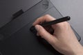 Artist draws on black graphic tablet close-up. designer`s hand with pen on graphic tablet