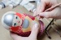 The artist draws a doll-matryoshka. Female hands with a brush close-up Royalty Free Stock Photo