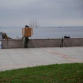 The artist draws a sketch of the picture sitting on the concrete fence of the sea embankment.