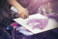 An artist draws on a white canvas with a pink spray paint graffiti