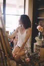 Artist girl paints picture on canvas in studio Royalty Free Stock Photo