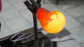 Artist glass blower changing on workbench the melted yellow red glass sticky ball to designed artwork. Glass crafter shaping