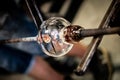 Artist glass blower working glass paste on his workbench. A glass crafter is burning and blowing an art piece