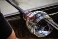 Artist glass blower working glass paste on his workbench. A glass crafter is burning and blowing an art piece Royalty Free Stock Photo