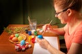 Artist designer woman paints Easter items. Egg and rabbit. Uses watercolor brushes. Works in the studio. Royalty Free Stock Photo