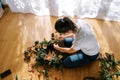 Artist makes a Christmas wreath from spruce branches and dried fruits lying on the floor. Top view