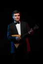 Artist musician, a dark-haired man in a black suit and a bow tie, plays a balalaika Royalty Free Stock Photo