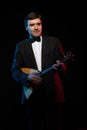 Artist musician, a dark-haired man in a black suit and a bow tie, plays a balalaika Royalty Free Stock Photo