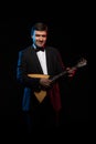 Artist musician, a dark-haired man in a black suit and a bow tie, plays a balalaika Royalty Free Stock Photo