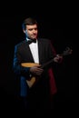Artist musician, a dark-haired man in a black suit and a bow tie, plays a balalaika Royalty Free Stock Photo