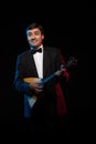 Artist musician, a dark-haired man in a black suit and a bow tie, plays a balalaika Royalty Free Stock Photo