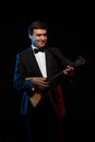 Artist musician, a dark-haired man in a black suit and a bow tie, plays a balalaika Royalty Free Stock Photo