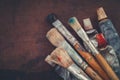 Artist Paintbrushes, Paint Tubes Closeup On Brown Canvas Background.