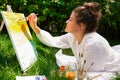 Artist painting on the easel outdoors in the garden. Open air outdoor art workshop. Draw on the canvas with brush and