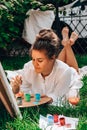 Artist painting on the easel outdoors in the garden. Open air outdoor art workshop. Draw on the canvas with brush and Royalty Free Stock Photo