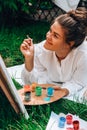 Artist painting on the easel outdoors in the garden. Open air outdoor art workshop. Draw on the canvas with brush and Royalty Free Stock Photo