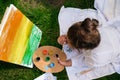 Artist painting on the easel outdoors in the garden. Open air outdoor art workshop. Draw on the canvas with brush and Royalty Free Stock Photo