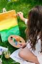 Artist painting on the easel outdoors in the garden. Open air outdoor art workshop. Draw on the canvas with brush and Royalty Free Stock Photo