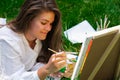 Artist painting on the easel outdoors in the garden. Open air outdoor art workshop. Draw on the canvas with brush and Royalty Free Stock Photo