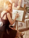 Artist painting on easel in studio. Girl paints with brush. Royalty Free Stock Photo