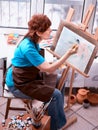 Artist painting easel in studio. Authentic senior woman.