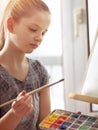 Artist painting on easel in studio. Girl paints with brush. Royalty Free Stock Photo