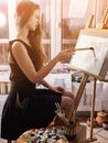 Artist painting on easel in studio. Girl paints with brush. Royalty Free Stock Photo