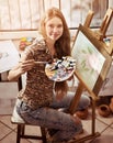 Artist painting on easel in studio. Girl paints with brush.