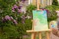 Artist painting on plein air in spring park, wooden easel and canvas standing outdoor with green background Royalty Free Stock Photo