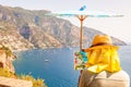 The artist painting scenery of a beautiful Positano city coast scenic rocky surroundings on one of a cliffs with blue sea waters