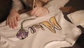 Woman is applying pattern on a white sweatshirt, close-up