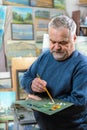 Artist paints oil painting with a brush and palette