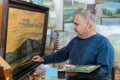 Artist paints oil painting with a brush and palette