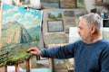 Artist paints oil painting with a brush and palette