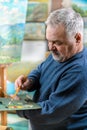 Artist paints oil painting with a brush and palette