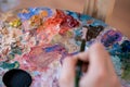 Artist paints a picture of oil paint brush in hand with palette closeup Royalty Free Stock Photo