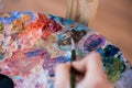 Artist paints a picture of oil paint brush in hand with palette closeup Royalty Free Stock Photo