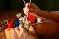 The hands of the artist paint the Easter bunny. Watercolor paints in jars and tubes. Handwork.