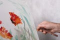 An artist with a palette knife paints red flowers on a white canvas Royalty Free Stock Photo