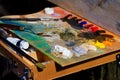 Artist palette with mixed fresh colorful oil paints in disorder, painter at work, outdoor plainair painting session, inspirational Royalty Free Stock Photo